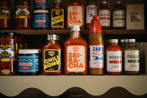 Bottles of hot sauce on a shelf with colorful labels