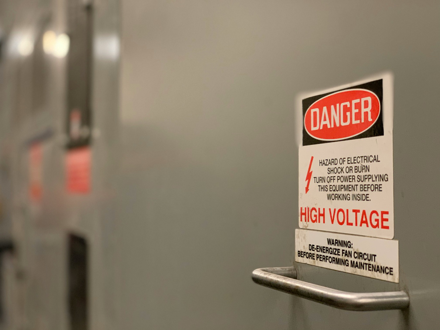 label on a door with a metal handle, warning users to maintain precaution