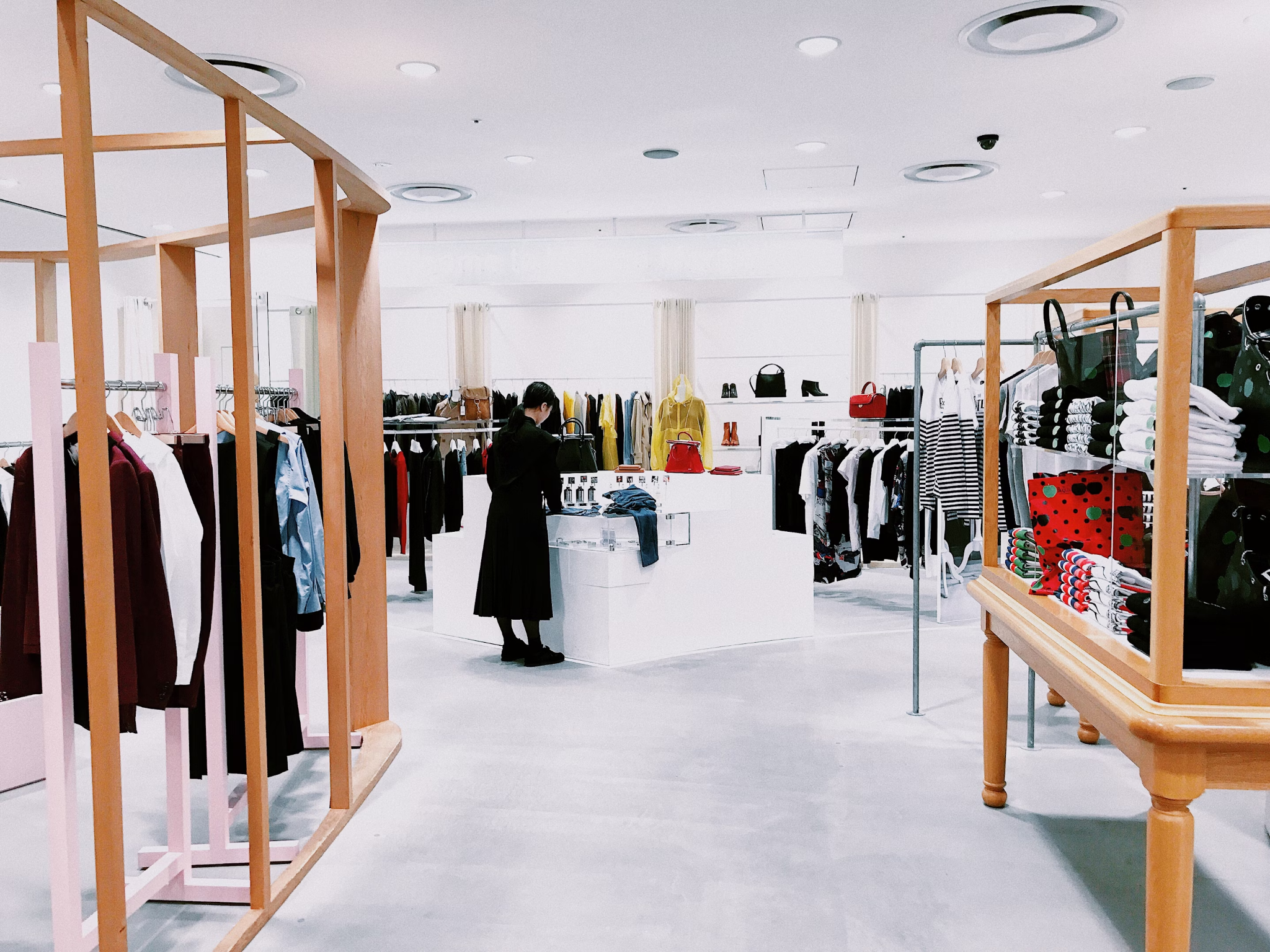 Woman browsing clothing racks in a retail store with well-lit, organized displays